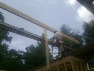 Carpenter setting a ridge beam over a new addition frame — Ice Dam Removal by Roofing Brothers in Reinbeck