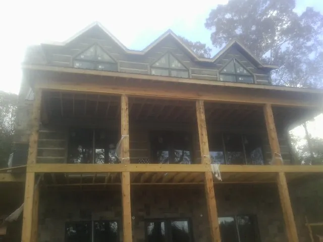 Dormers and porch framing on a large log home under construction — Roof Coating work by our crew in Reinbeck