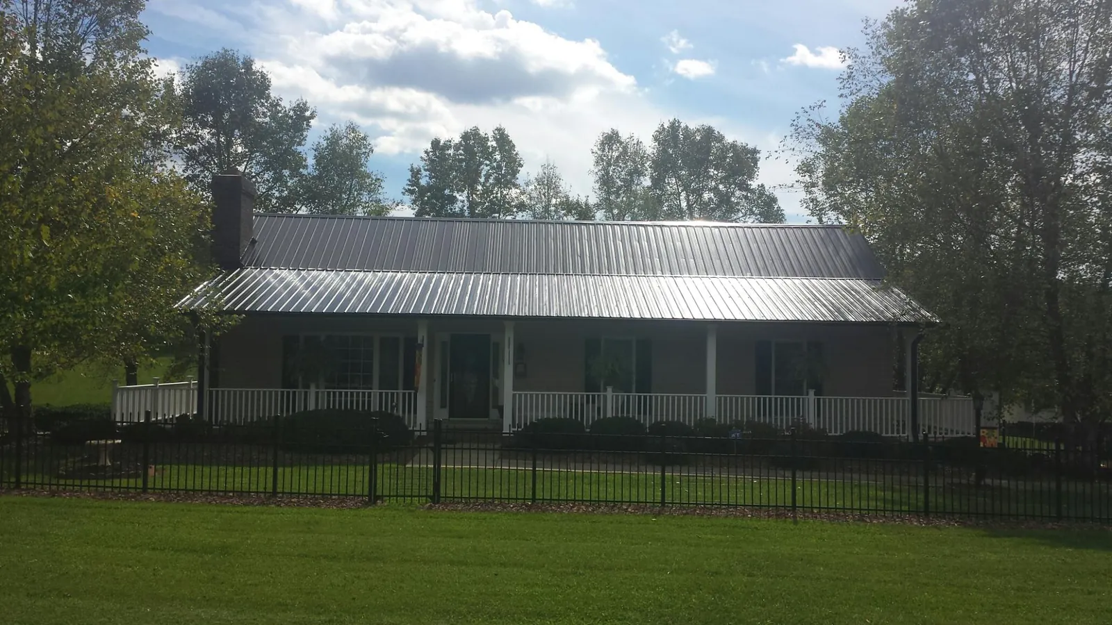 Gray metal roof on a brick ranch with a full width front porch — Gutter Guard Installation work by our crew in Reinbeck