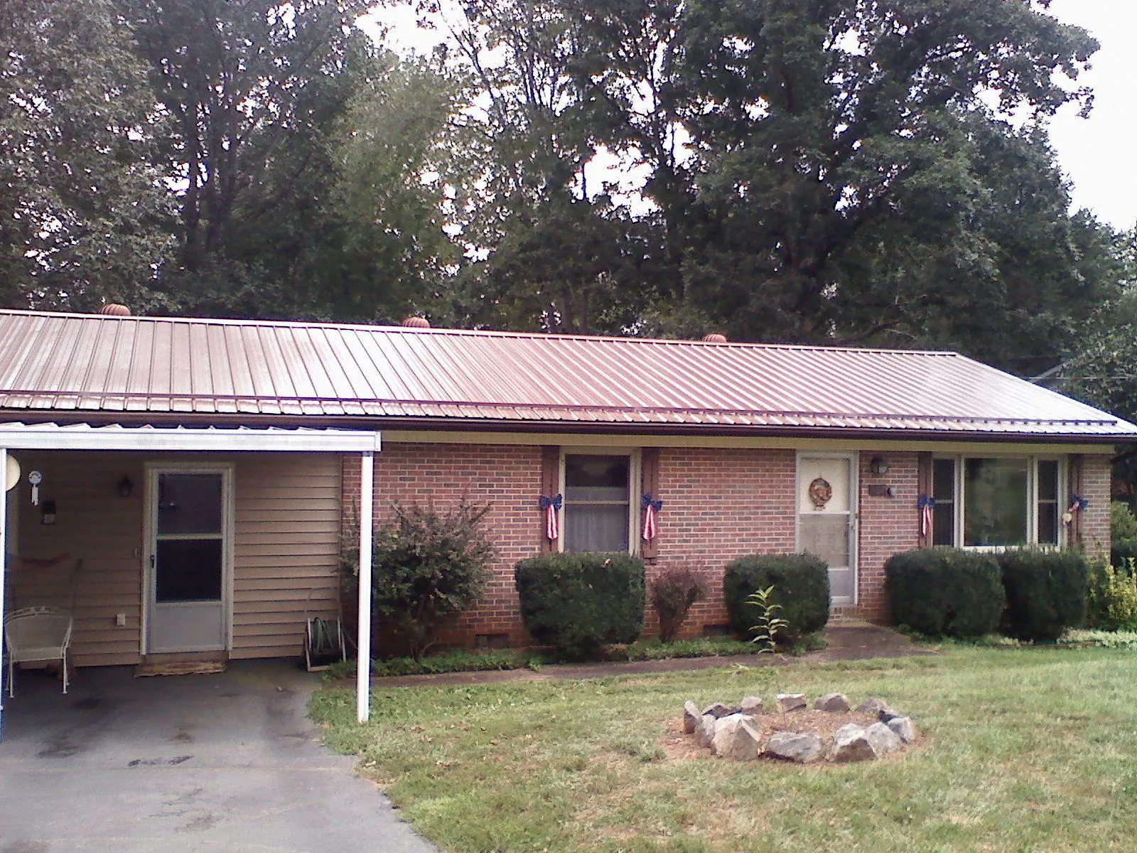 Bronze metal roof and carport on a brick ranch home — Roof Repair work by our crew in Reinbeck