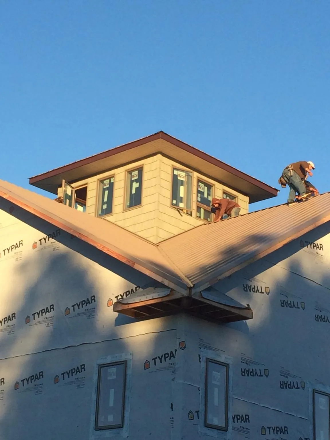 Roofers working around a rooftop cupola on a new metal roof at sunset — Roof Waterproofing in Reinbeck by Roofing Brothers
